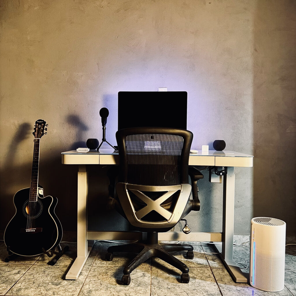 Sensibo Pure on floor next to a white desk with an iMac and pair of HomePod minis