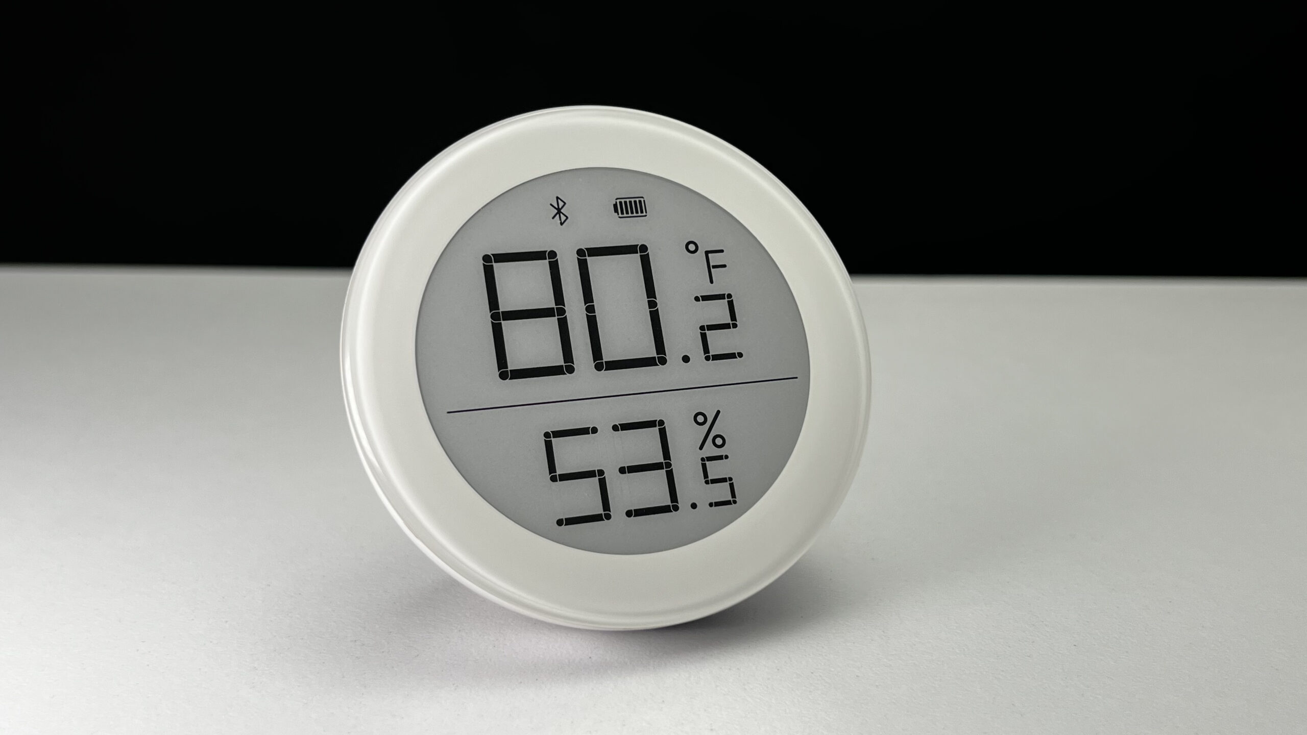 a circular white sensor with a large display showing the current temperature and humidity, the QingPing Temperature & Humidity Sensor