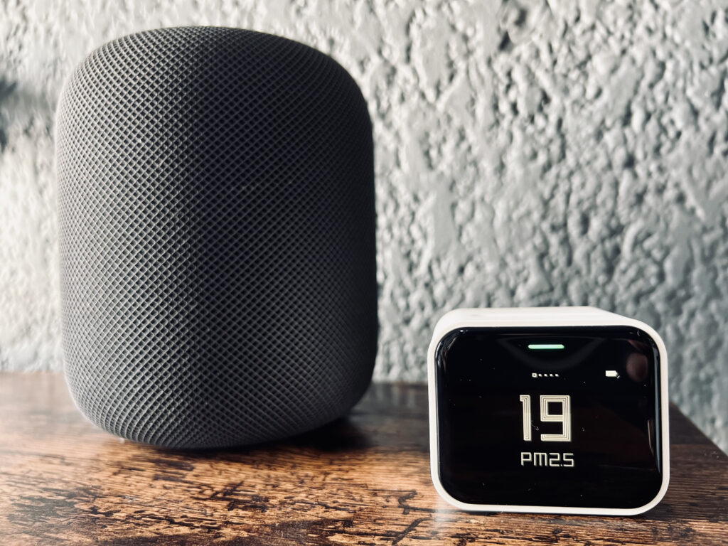 Air Monitor Lite displaying PM 2.5 levels on dark wooden surface next to an original HomePod