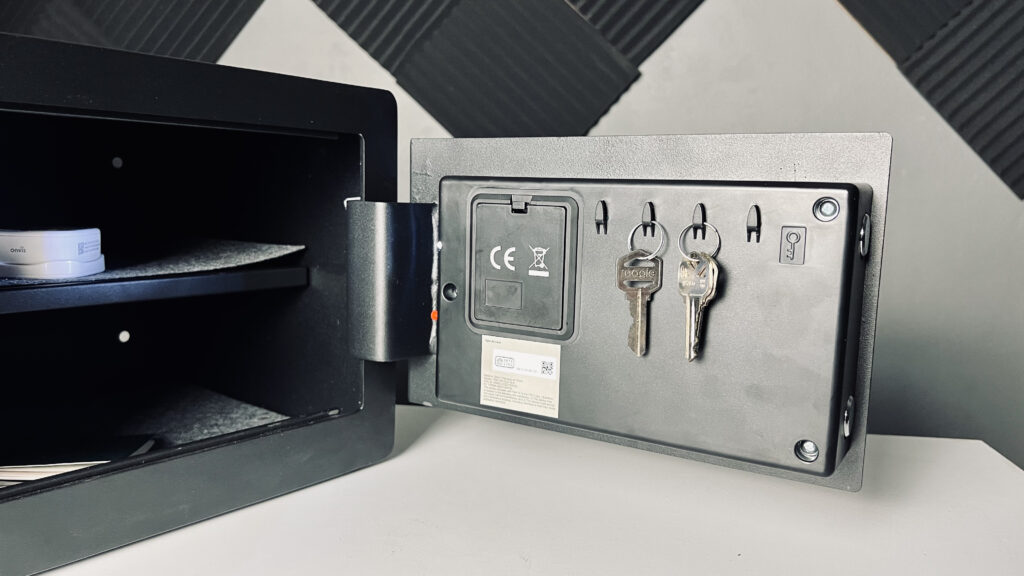 an opened Yale Smart Safe with keys hanging on the inside of the door and other valuables on the interior shelves