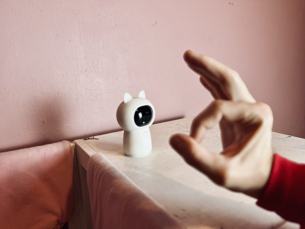 G3 against a pink wall with a person making the 'OK' hand sign toward the lens