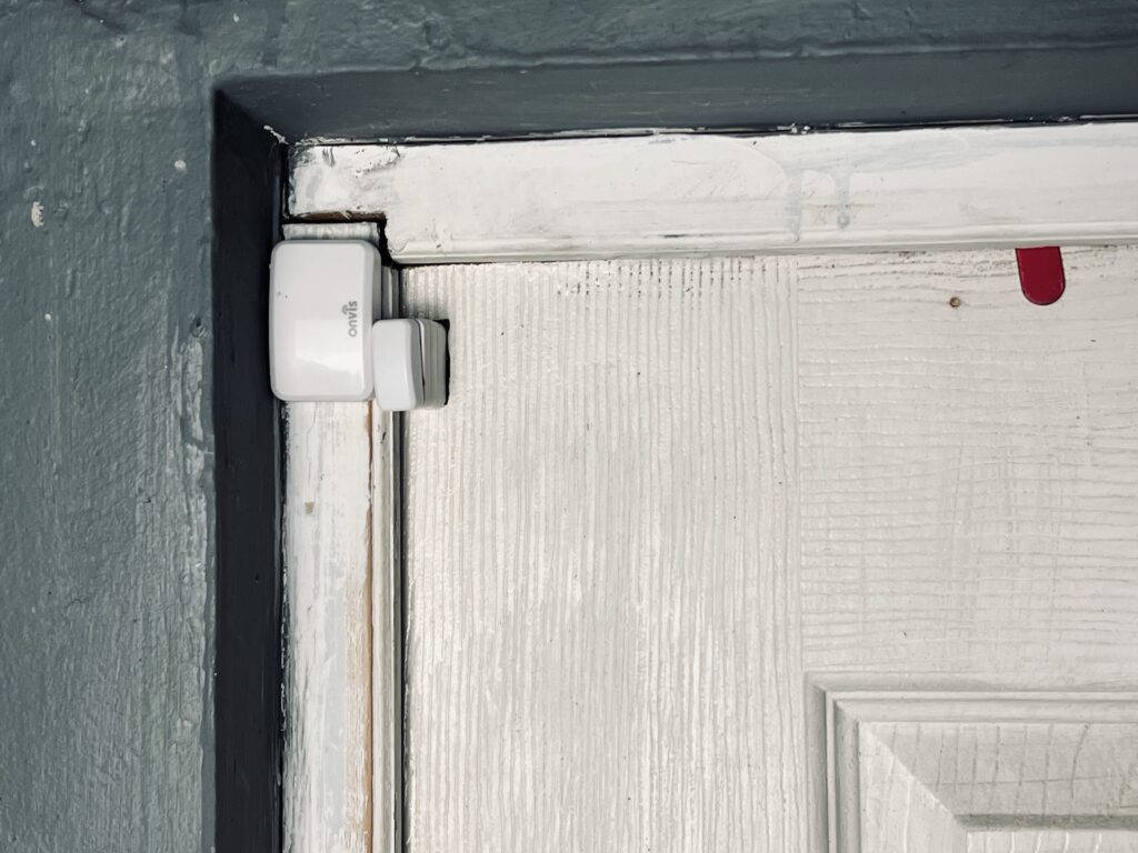 The Onvis CT3 Door & Window Sensor mounted vertically on a wooden door frame