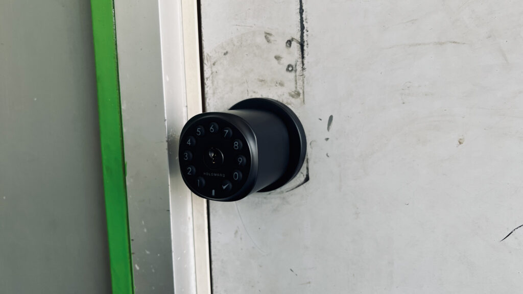 Matte black Sequra Smart Door Knob installed on a gray exterior door