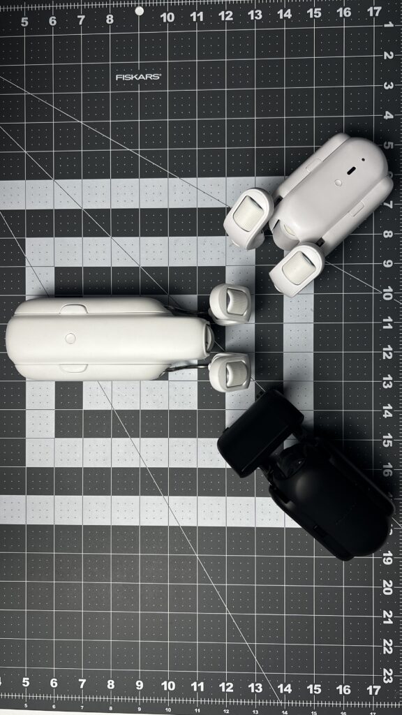 3 generations of the SwitchBot Curtain motors on a gray desk mat